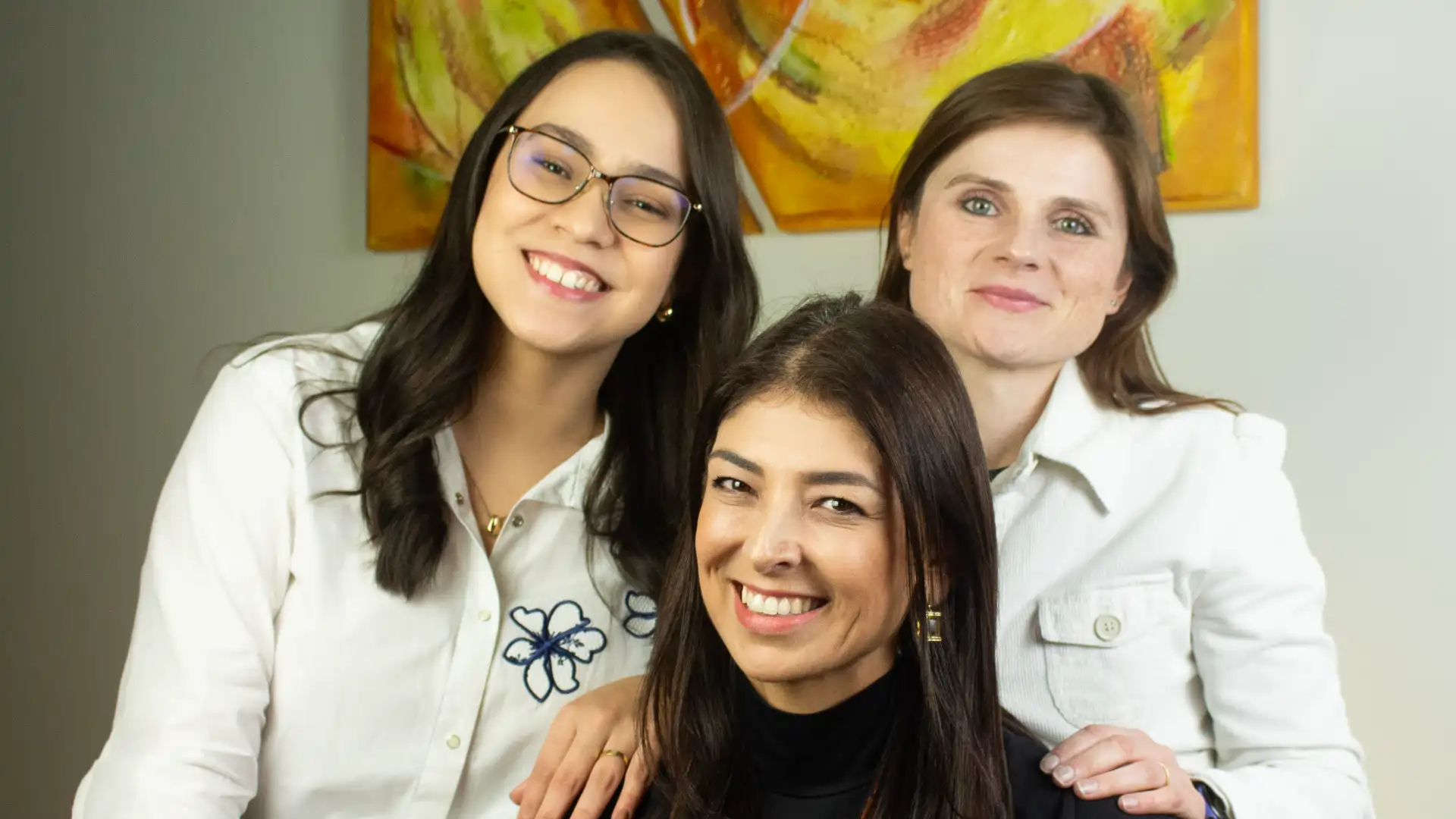 Três psicólogas do CDIF juntas, sorrindo, na sala de atendimento da clínica